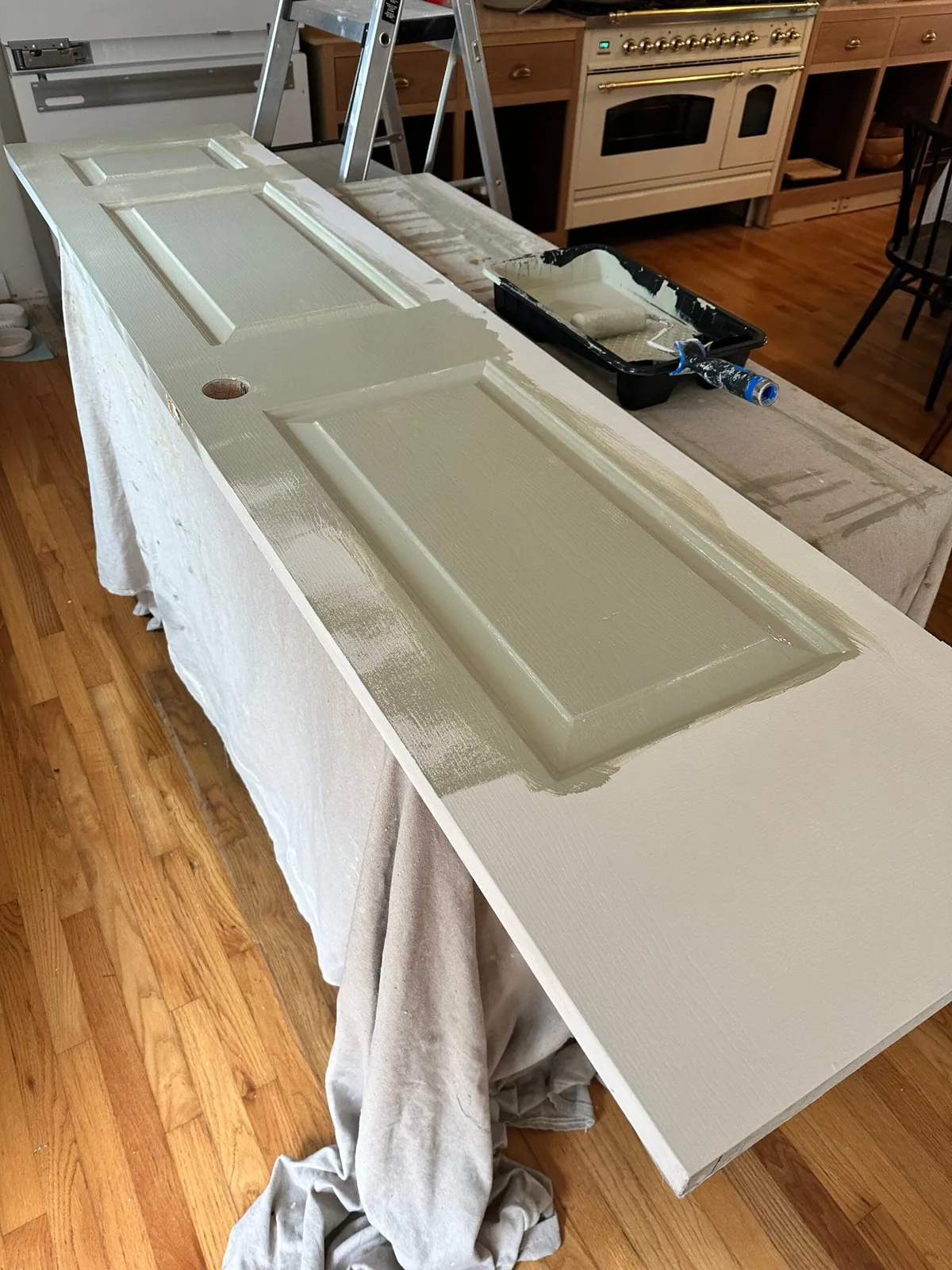Paneled door laid across trestles and rolled with sage green paint