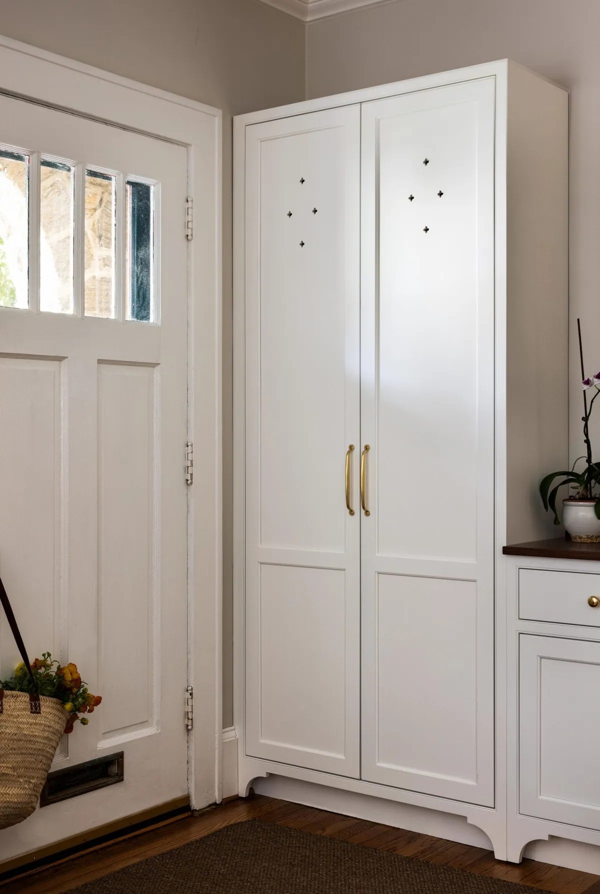 Entry with a floor to ceiling white storage cabinet beside the front door