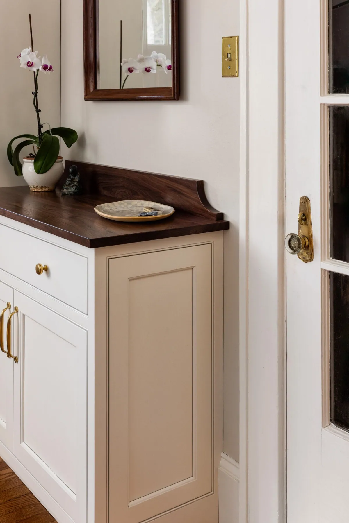Entry cabinet with a walnut top, an orchid and a small mirror above