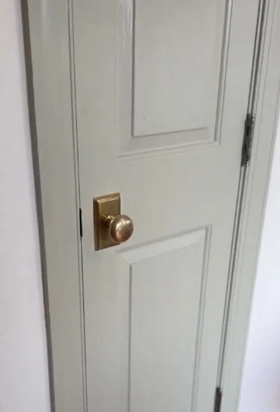Sage green painted closet door with an aged brass knob