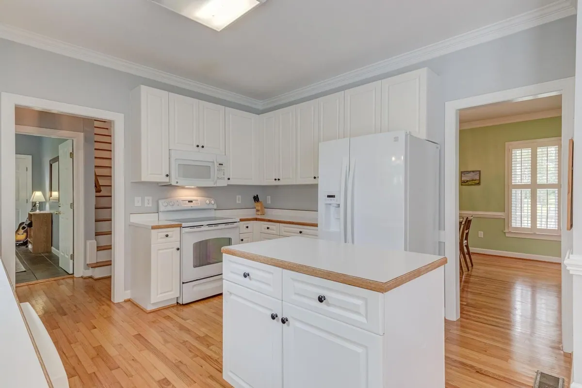 Dated white kitchen with a small butcher block island before renovation