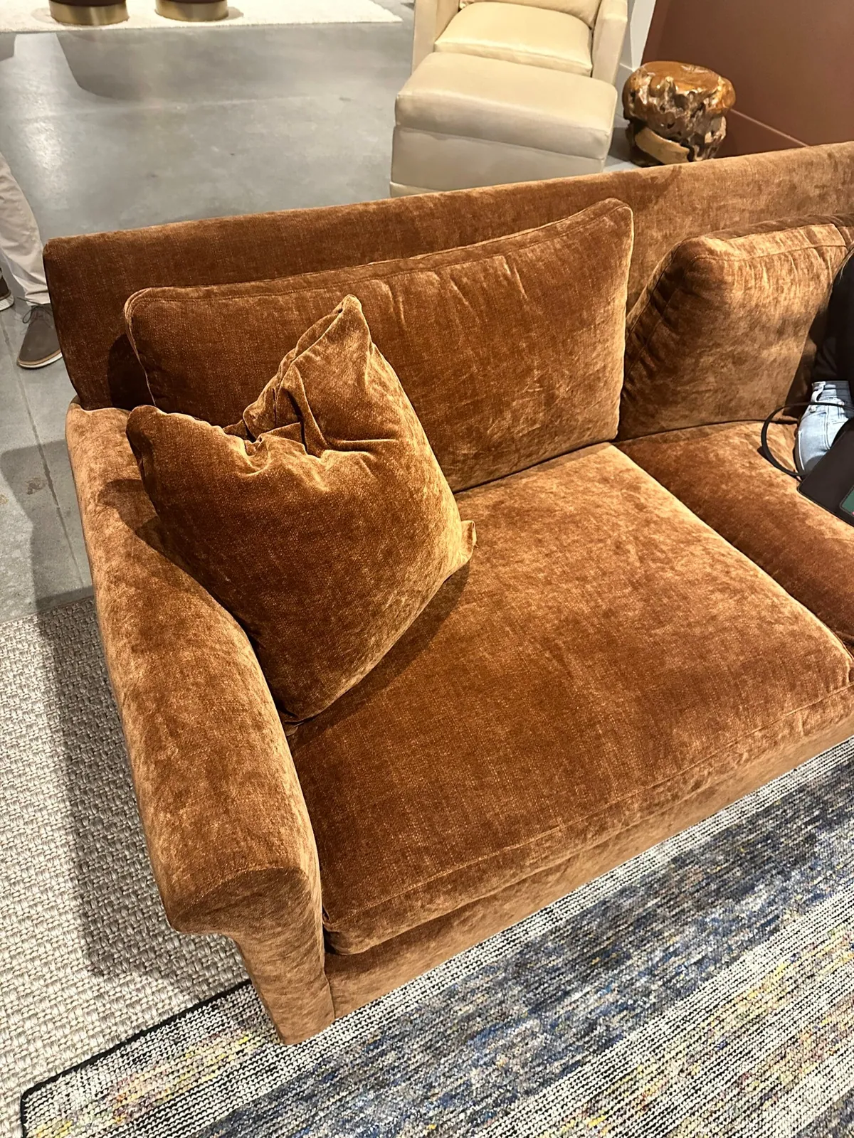 Caramel velvet armchair with loose cushions on a furniture showroom floor