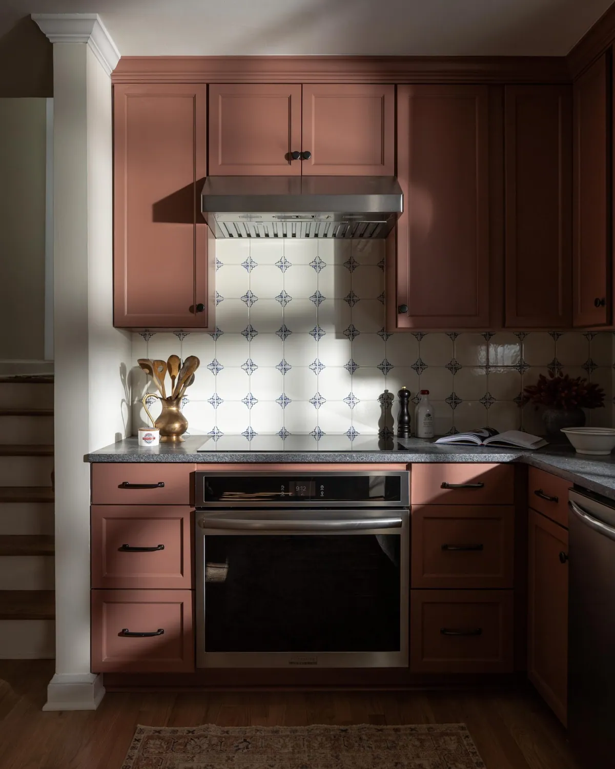 Terracotta pink kitchen with a stainless hood, wall oven and blue and white tile