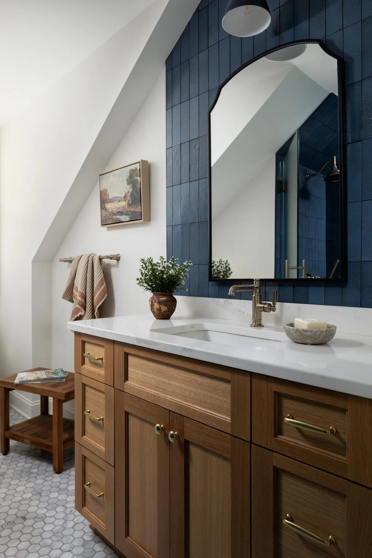 Bathroom with deep blue vertical tile, white oak vanity, black arched mirror and marble hexagon floor