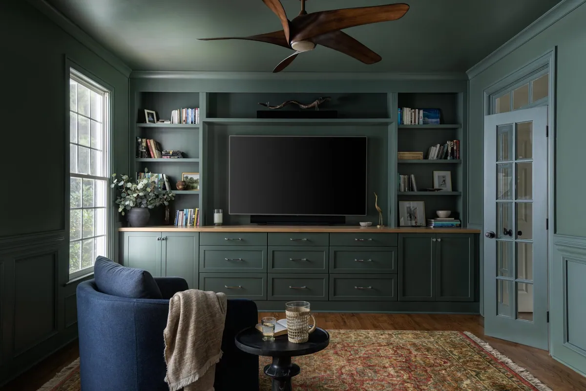 Library with built-in cabinetry, dark green millwork, and a cozy seating nook.