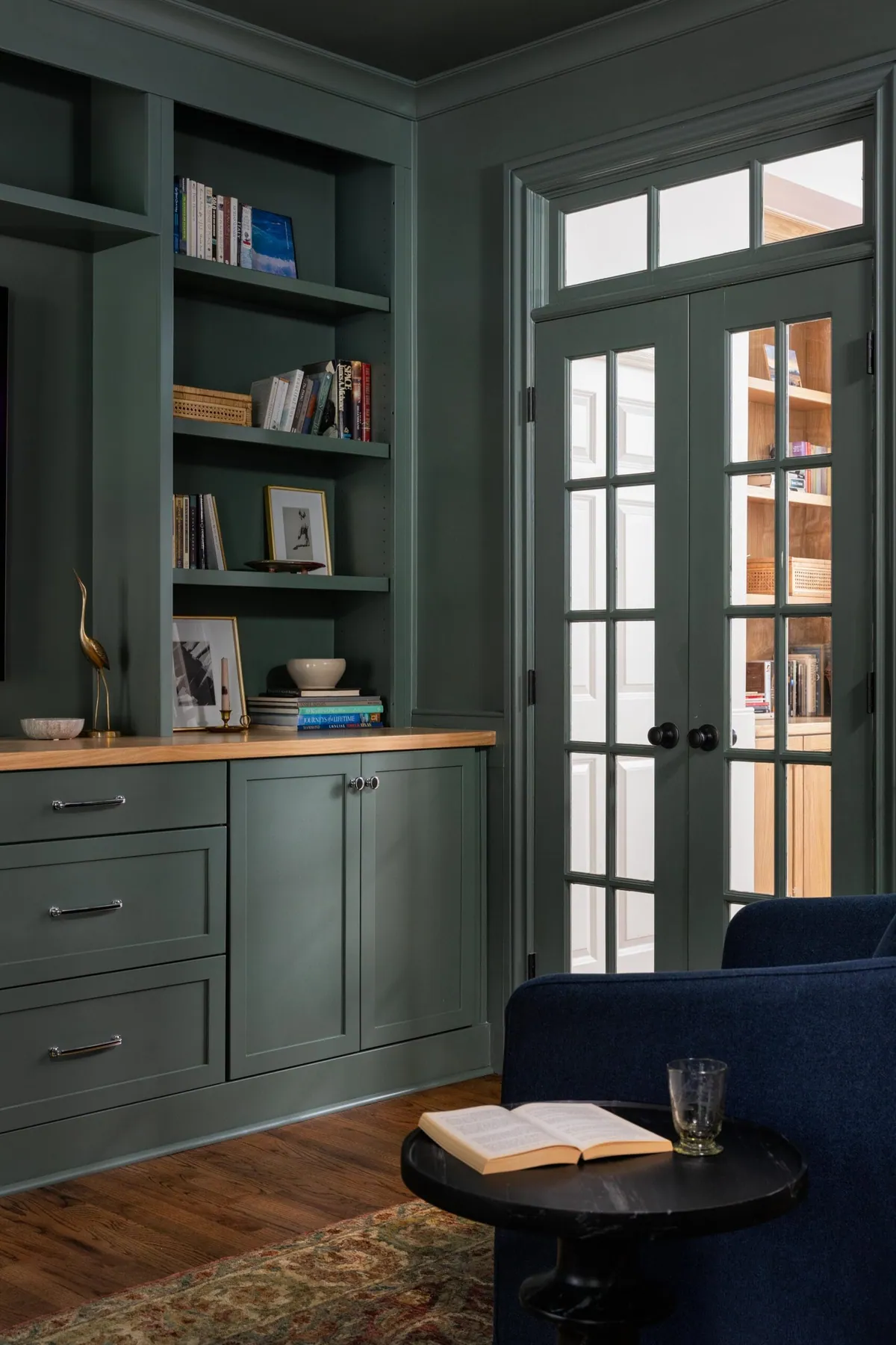 Library with built-in cabinetry, dark green millwork, and a cozy seating nook