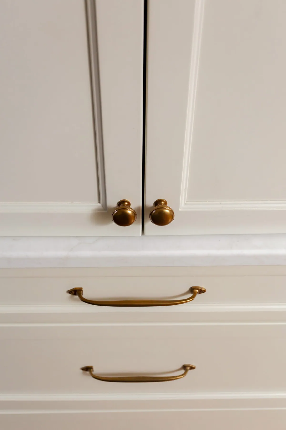 Cabinet doors and drawers detailed with aged brass knobs and bin pulls
