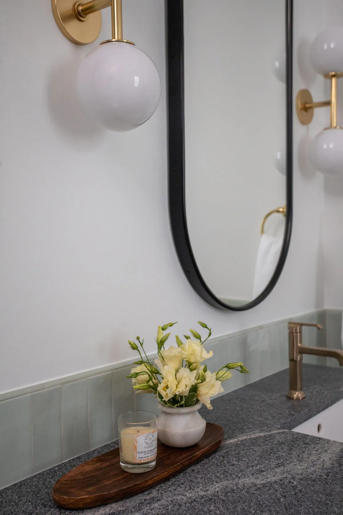 Brass globe sconce beside an oval mirror