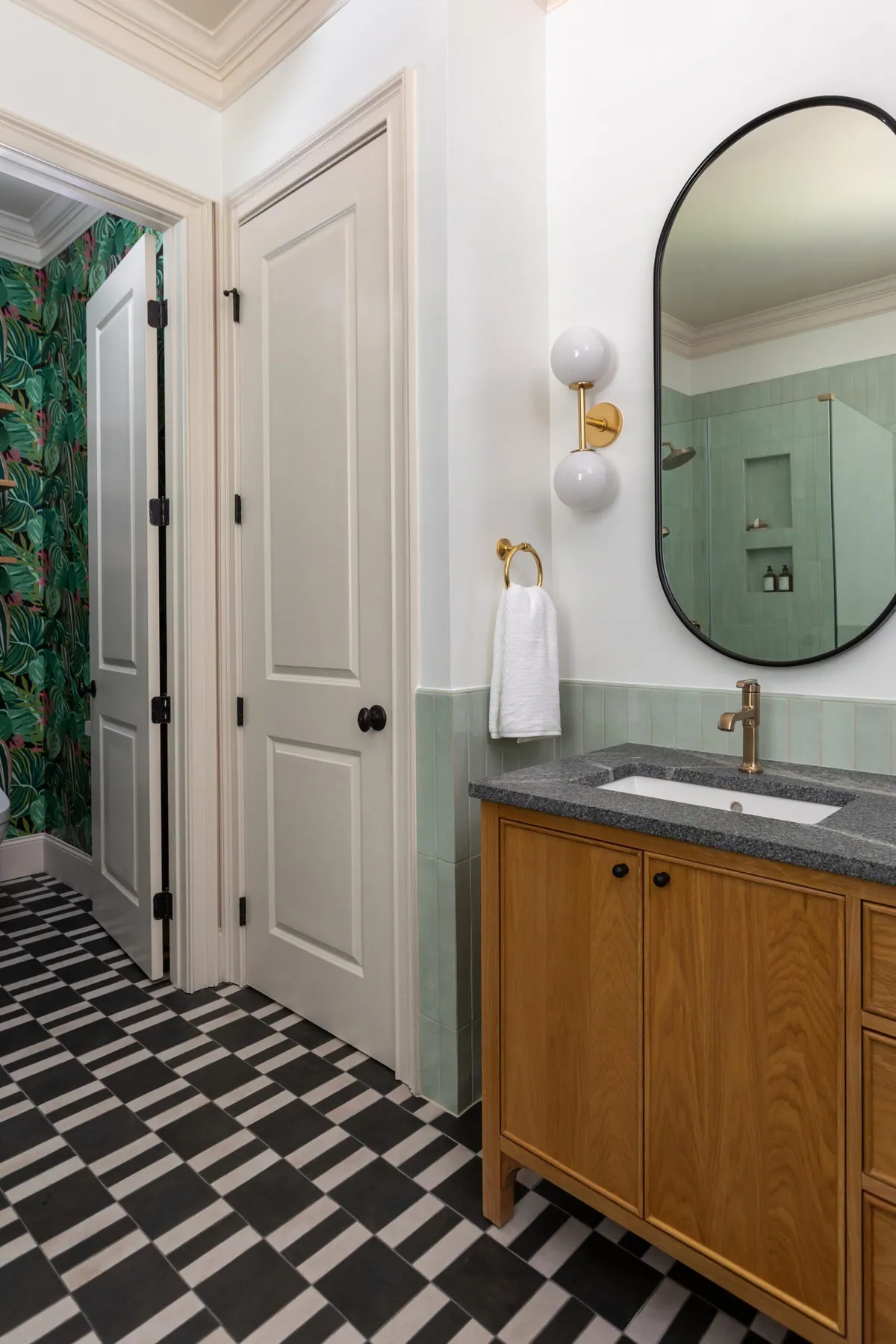 White oak vanity beside the water closet with tropical wallpaper
