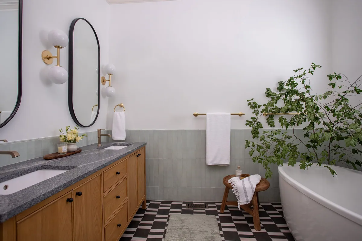 Primary bathroom in Fuquay-Varina with a white oak double vanity, celadon tile, a patterned tile floor and a freestanding tub