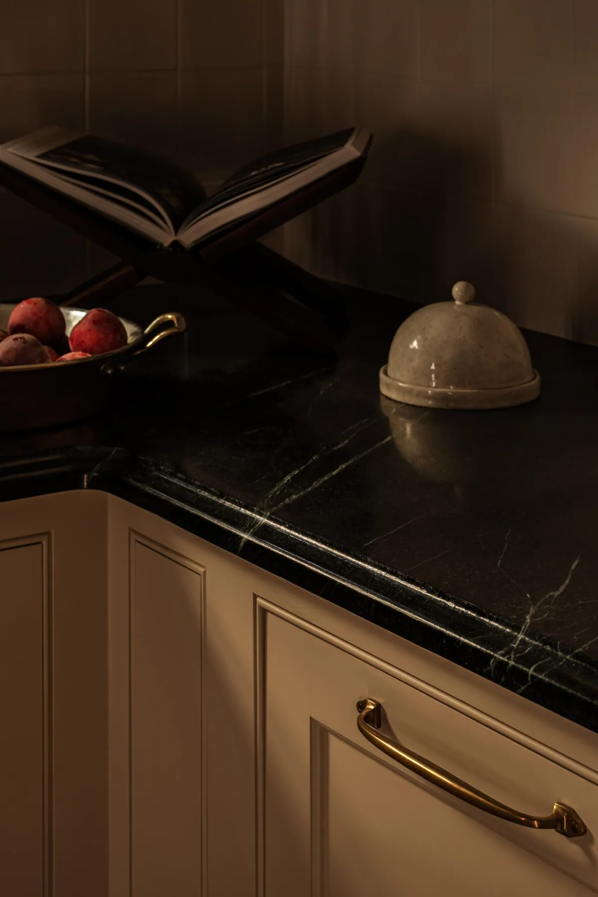 Soapstone countertop with a copper bowl, cookbook stand and aged brass bin pull