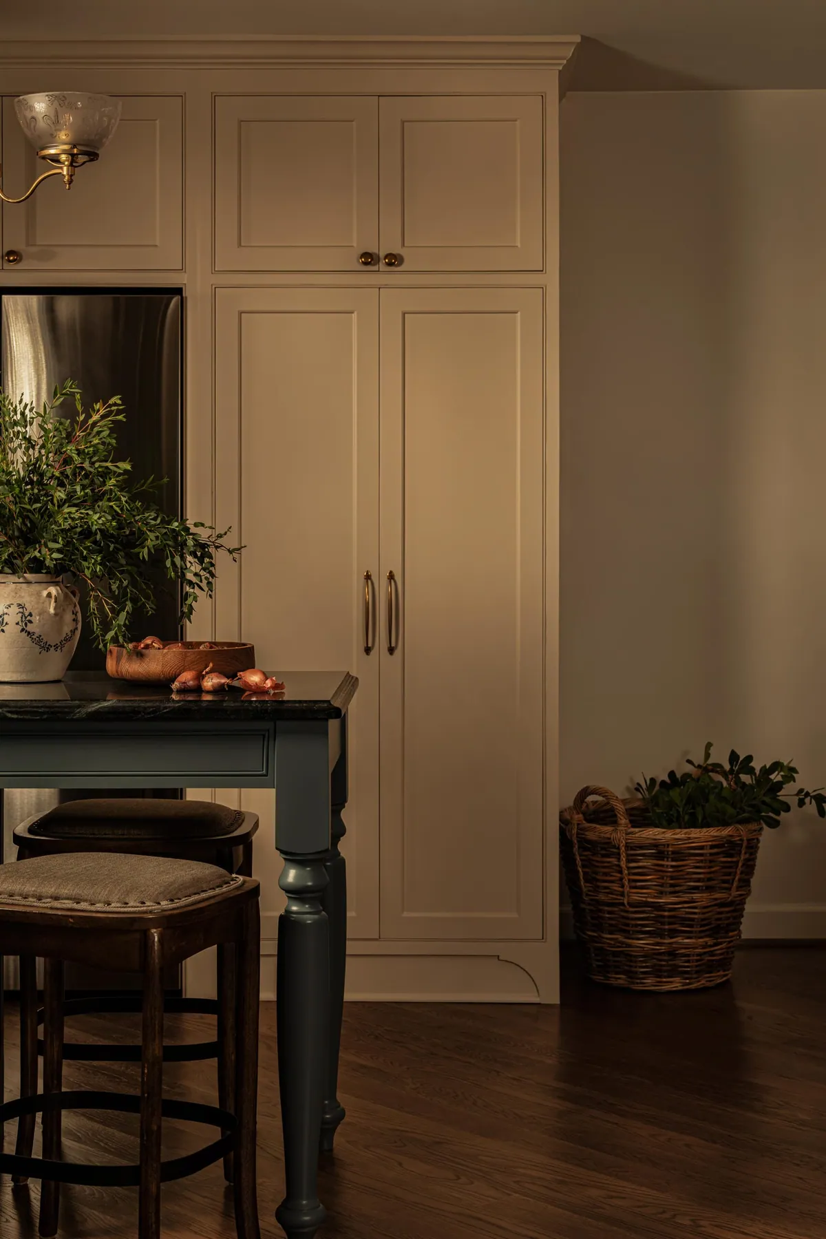 Floor to ceiling cream pantry cabinetry beside a gray-blue island