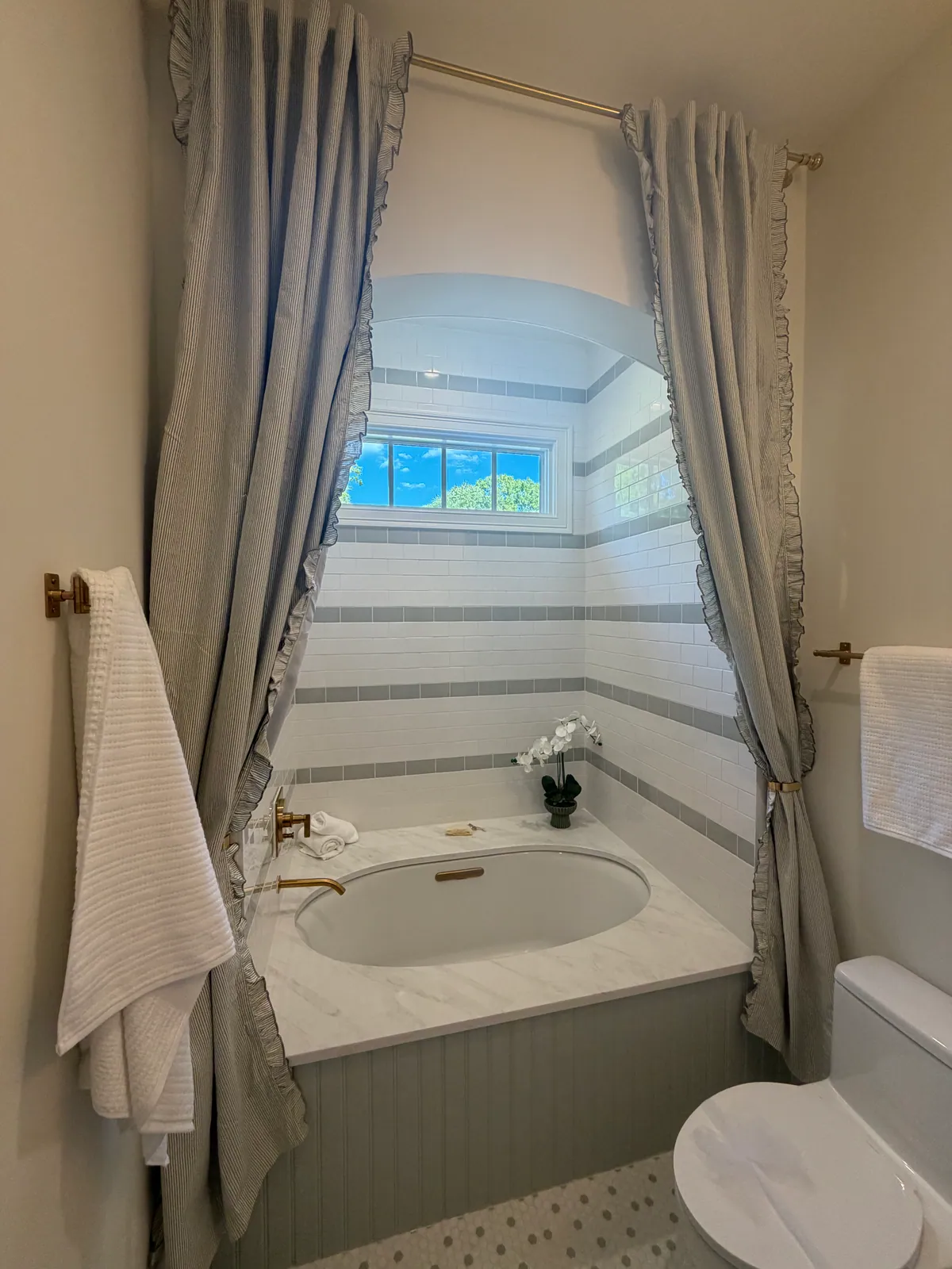Bathtub in an arched alcove with drapery panels tied back on either side