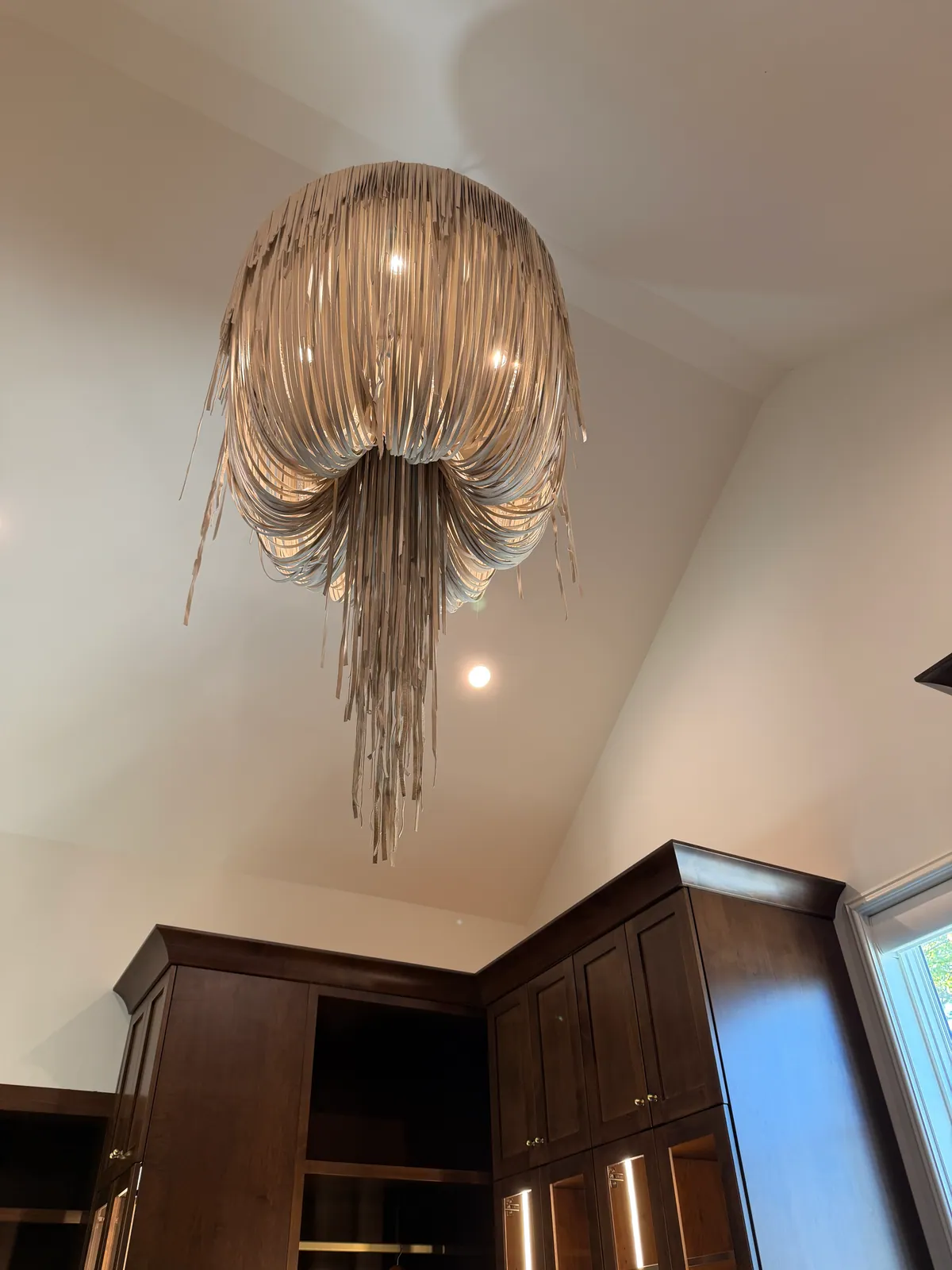 Cascading fringe chandelier in a closet with dark wood cabinetry
