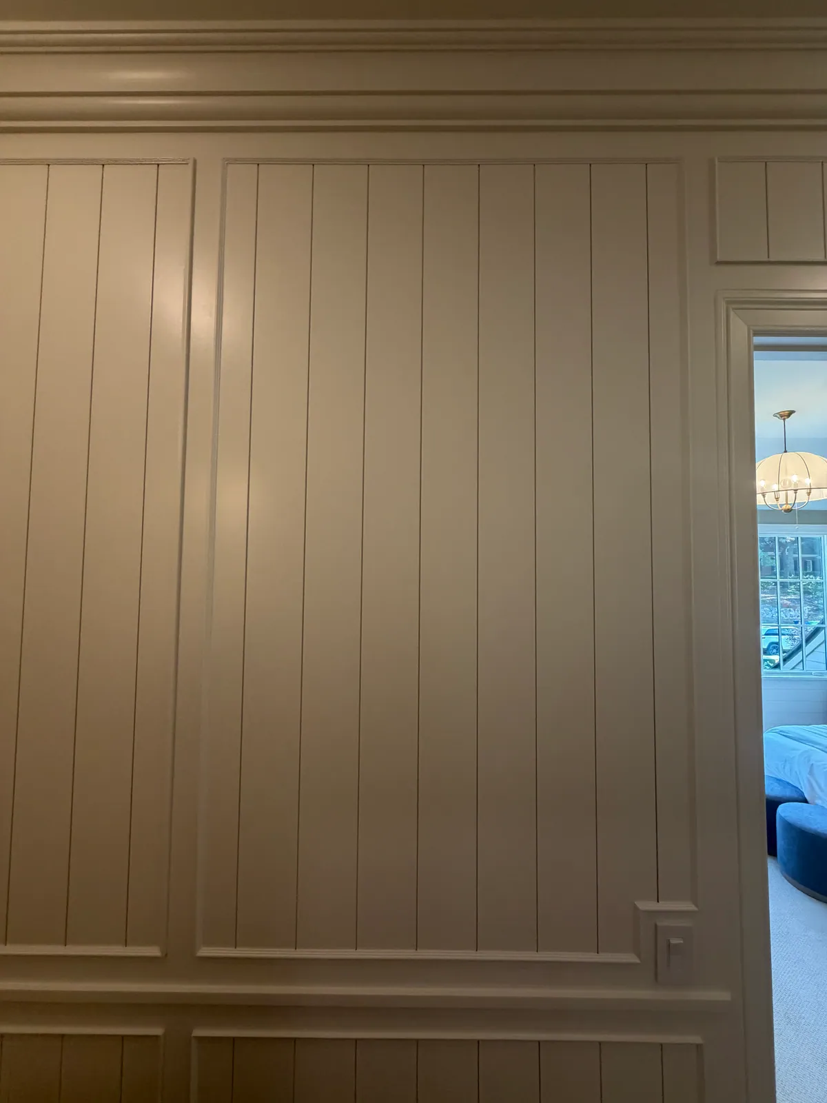 Wall paneling painted warm greige, with vertical boards above a framed panel