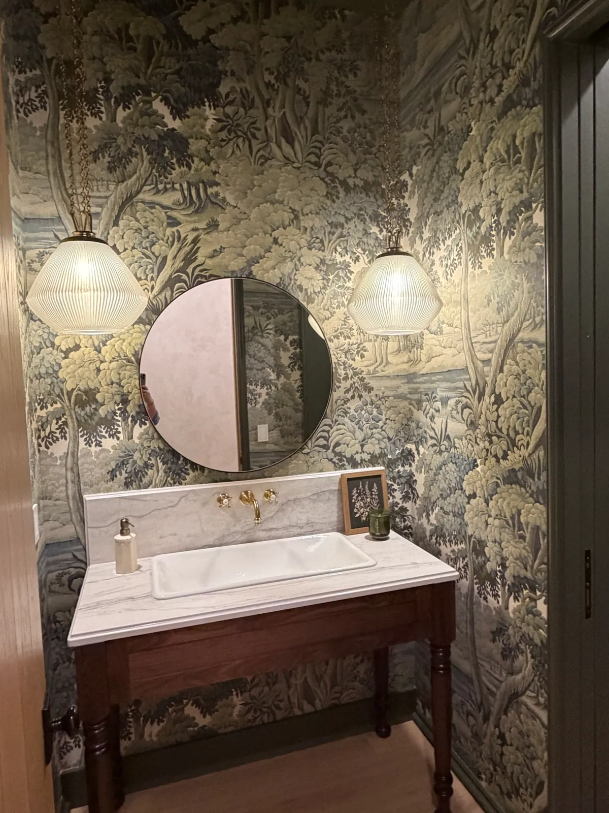 Powder room with scenic wallpaper, a round mirror and a pendant light on each side