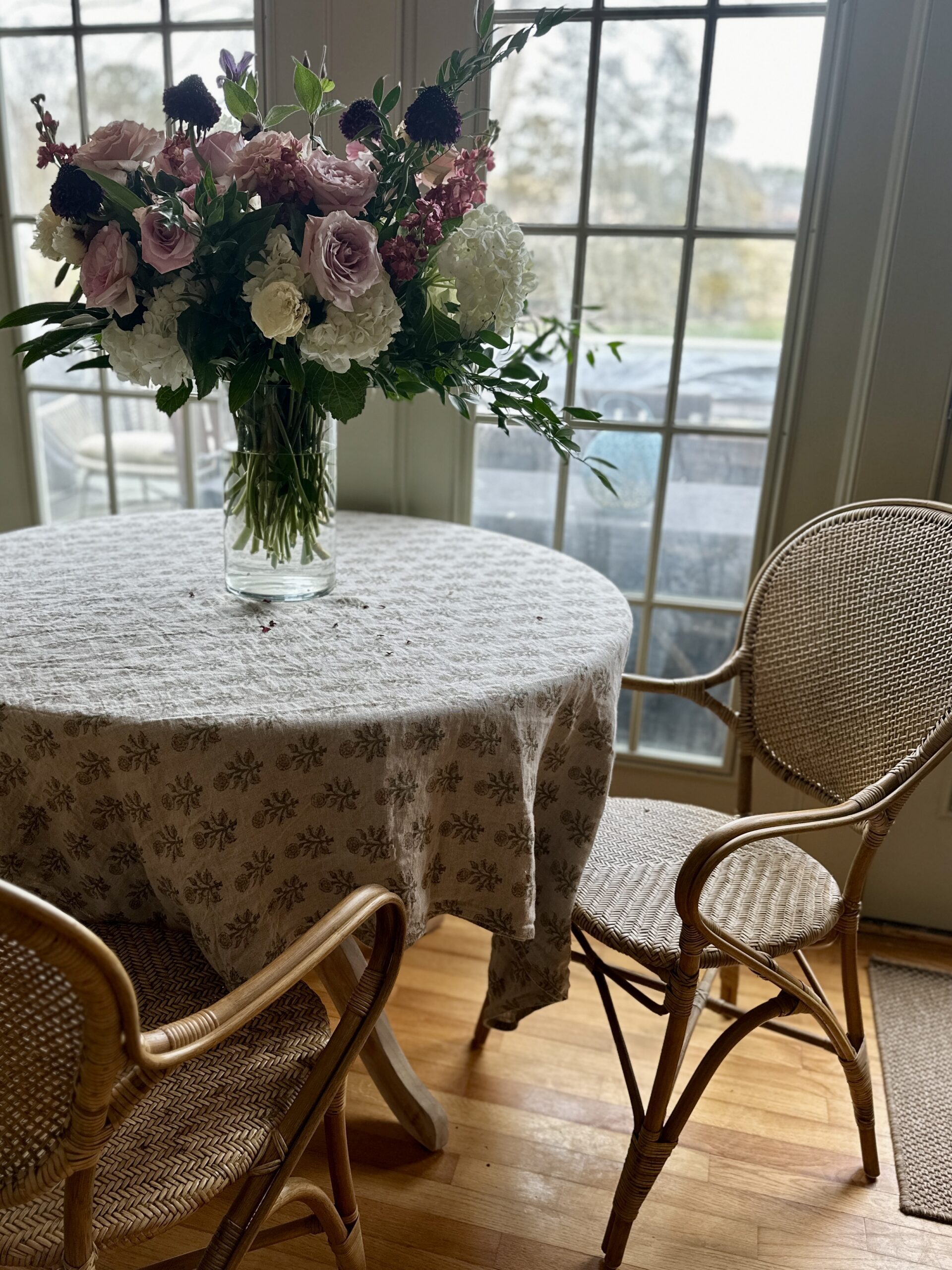 cozy breakfast table with rattan chairs, flowers, romantic table scene