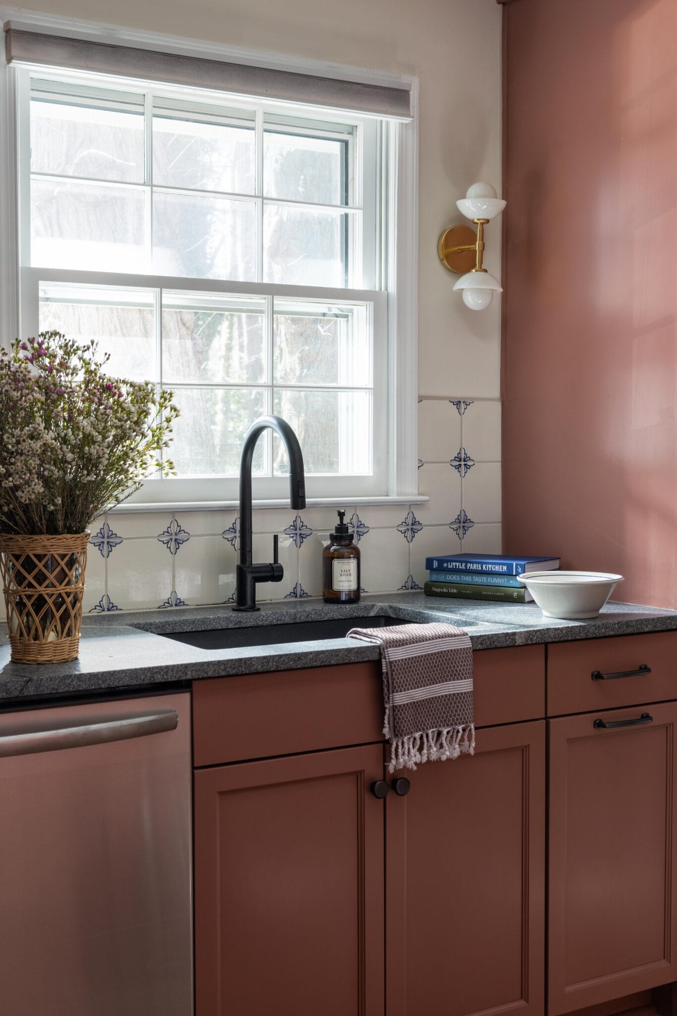 Terracotta pink kitchen with a black faucet and patterned tile above the sink