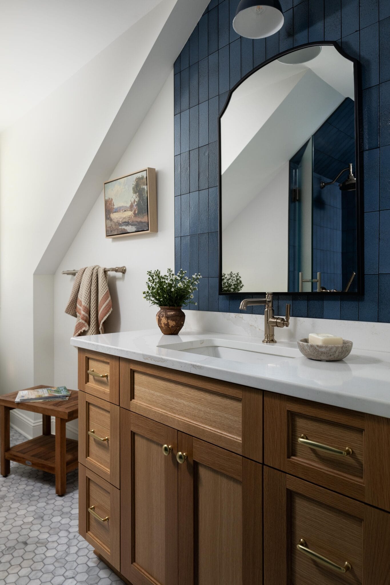 Bathroom with deep blue vertical tile, white oak vanity, black arched mirror and marble hexagon floor