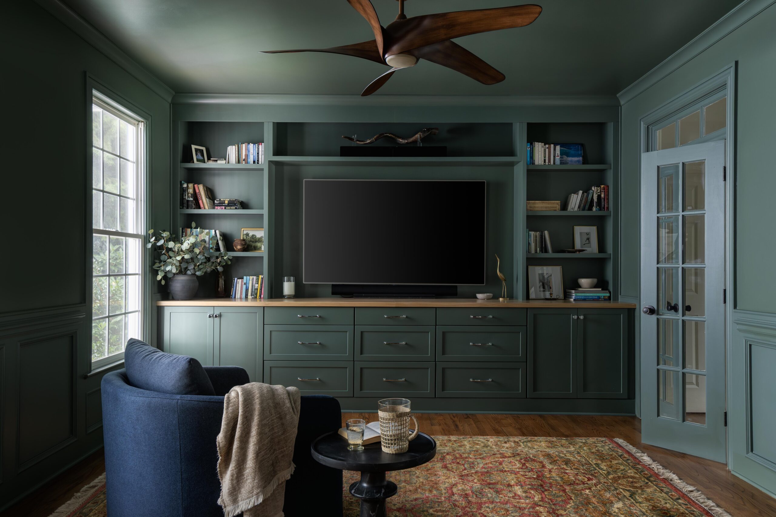 Library with built-in cabinetry, dark green millwork, and a cozy seating nook.