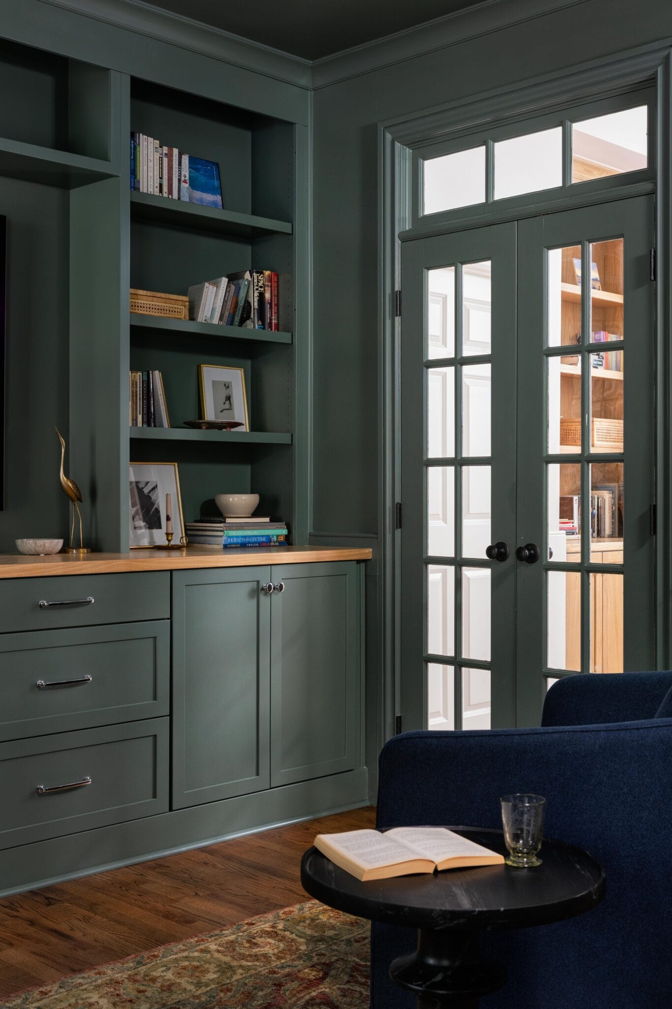 Library with built-in cabinetry, dark green millwork, and a cozy seating nook