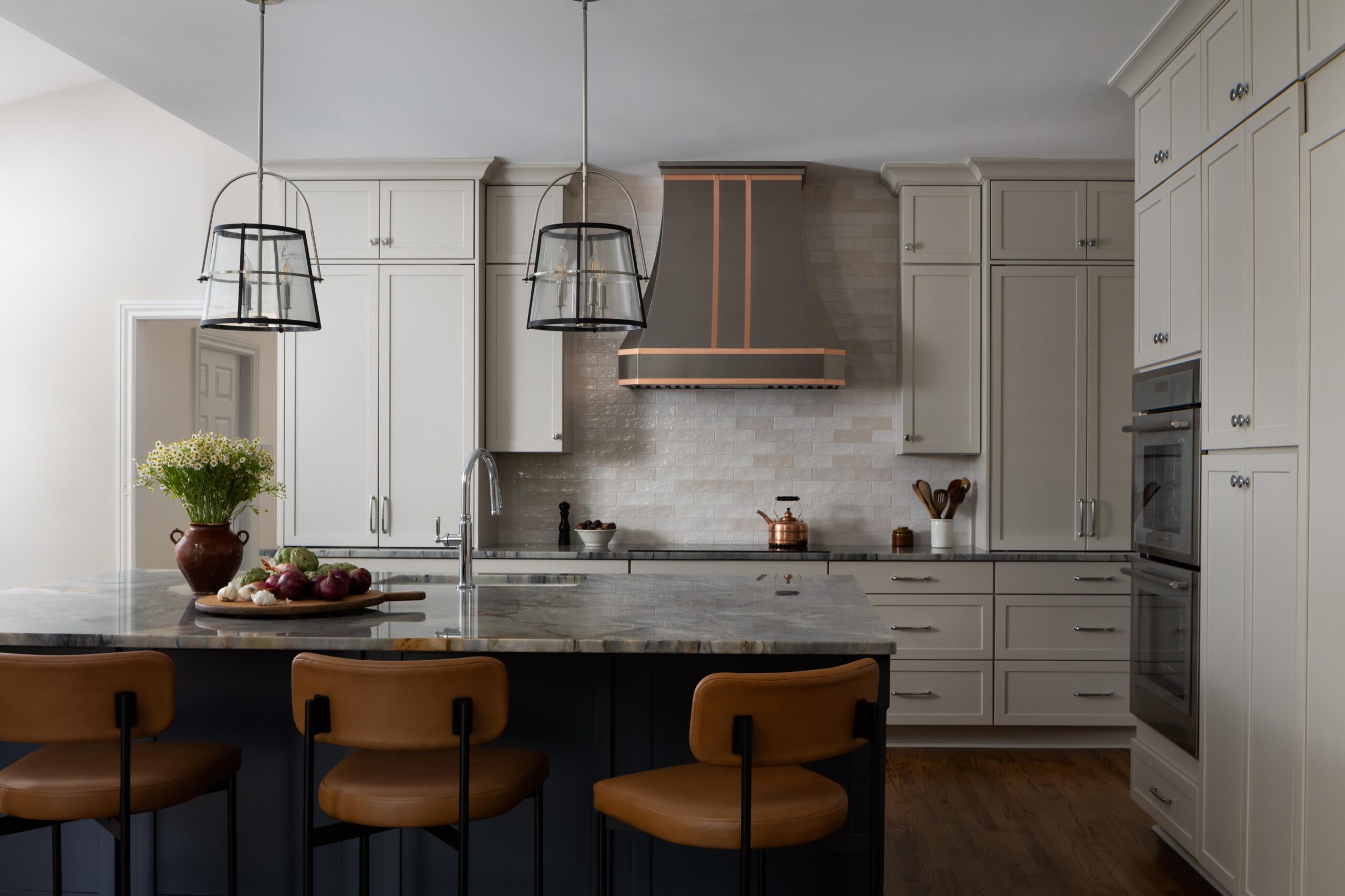 Raleigh transitional kitchen with marble island, leather stools, white cabinetry, and copper range hood