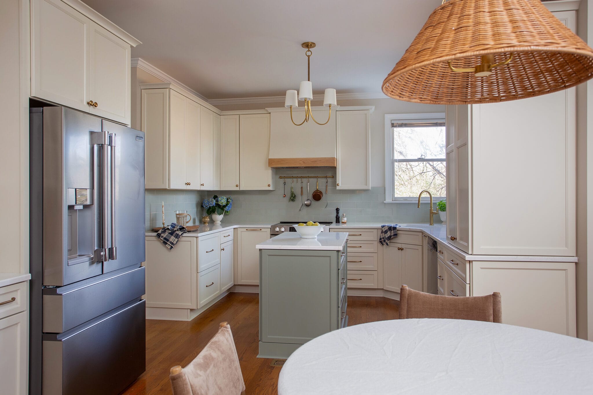 Kitchen with a woven rattan pendant, pale blue backsplash and a round breakfast table