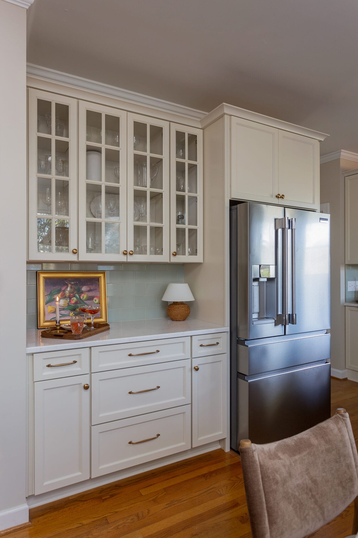 Glass-front upper cabinets and a built-in buffet beside a counter-depth refrigerator